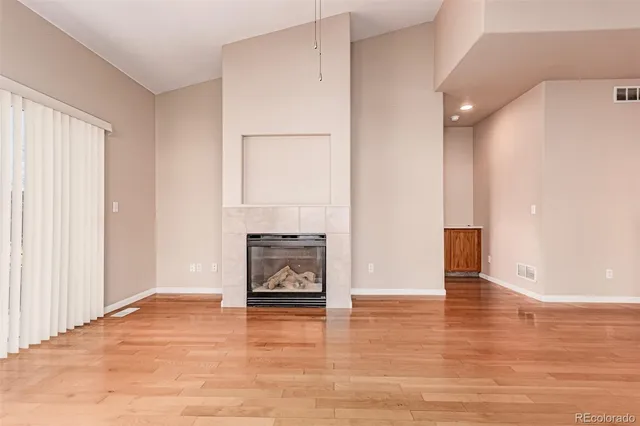 a view of empty room with wooden floor and fireplace