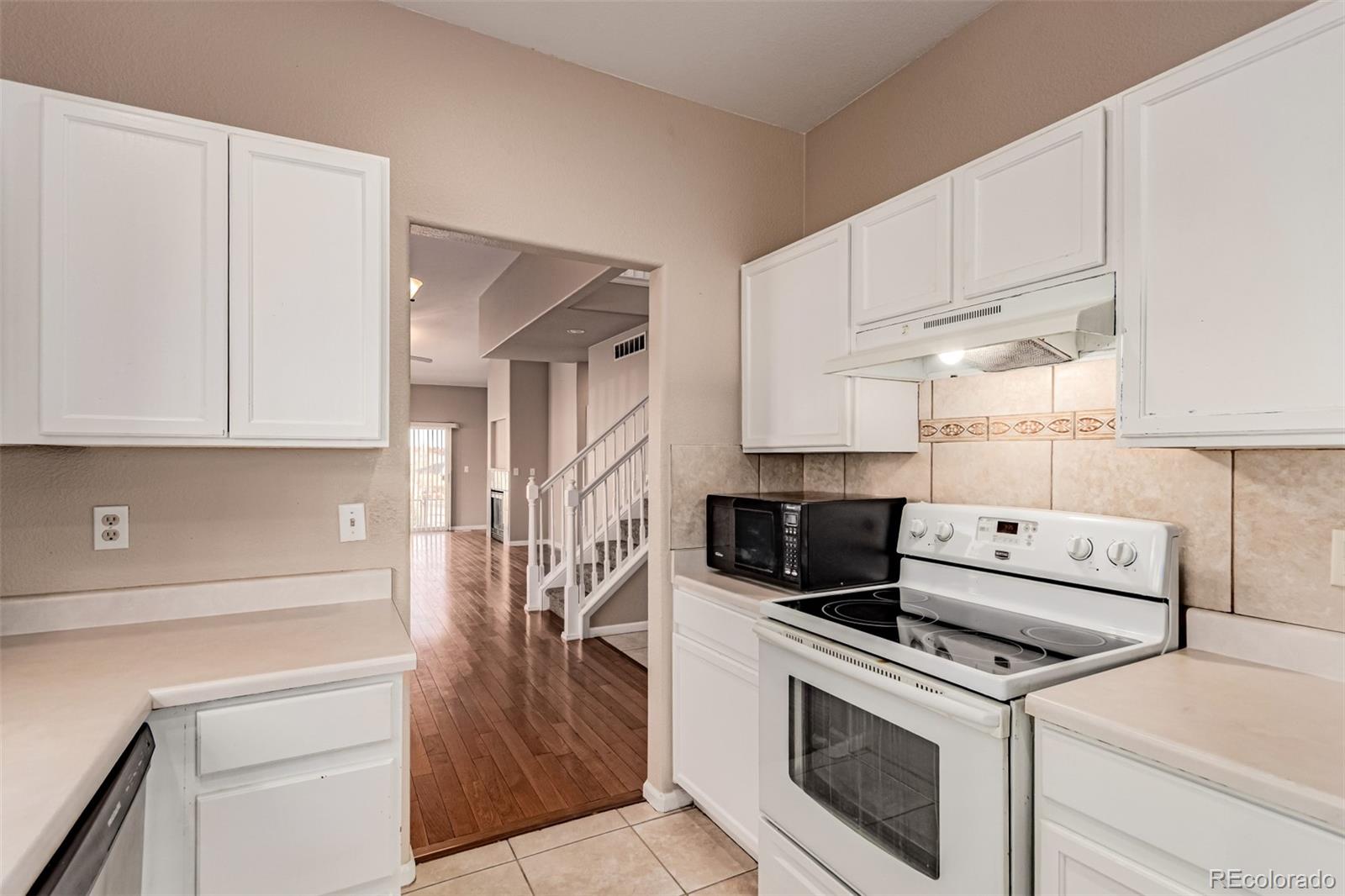 4538 South Atchison Way Aurora, CO 80015 - Photo 20 of 50 a kitchen with white cabinets and white appliances