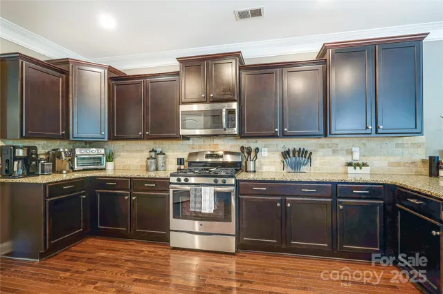 a kitchen with stainless steel appliances granite countertop wooden cabinets a stove top oven with a sink and dishwasher
