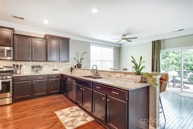 a large kitchen with stainless steel appliances granite countertop a sink and wooden cabinets