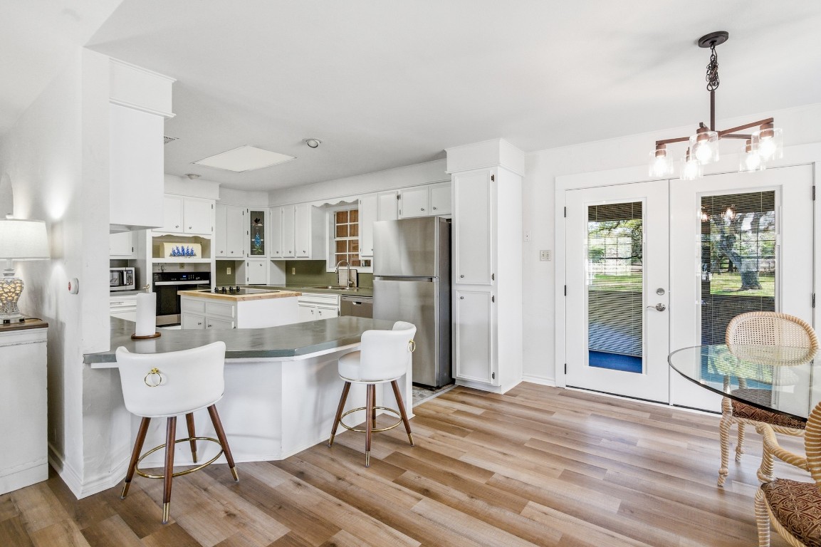11847 Friar Road Cuero, TX 77954 - Photo 33 of 50 a kitchen with stainless steel appliances kitchen island granite countertop a refrigerator a stove top oven a sink dishwasher and white cabinets with wooden floor