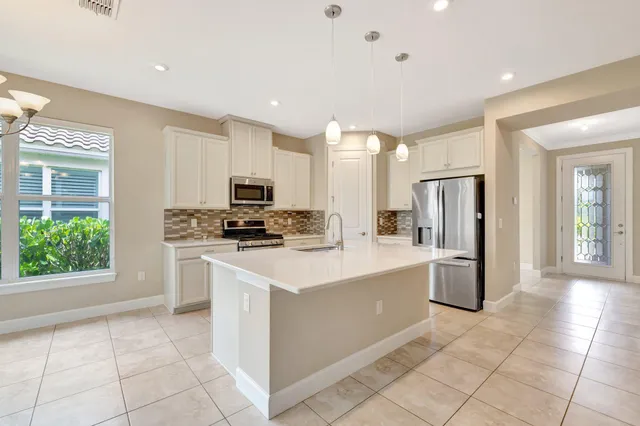 a kitchen with a sink a stove a refrigerator and white cabinets