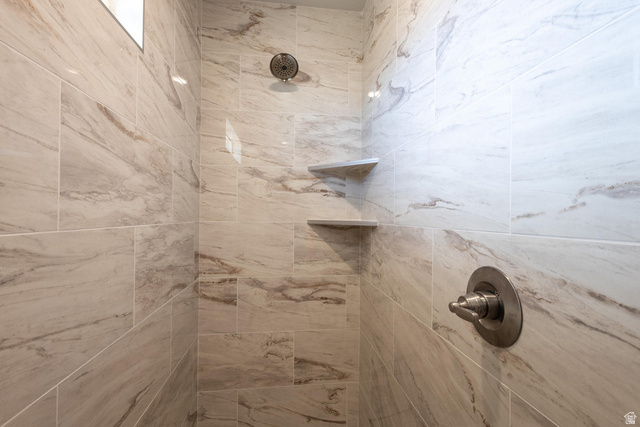 910 East Remington Road Cedar City, UT 84721 - Photo 22 of 29 Shower interior featuring large-format tile with subtle veining, dual built-in shelving, a rainfall showerhead, and a single-handle control valve