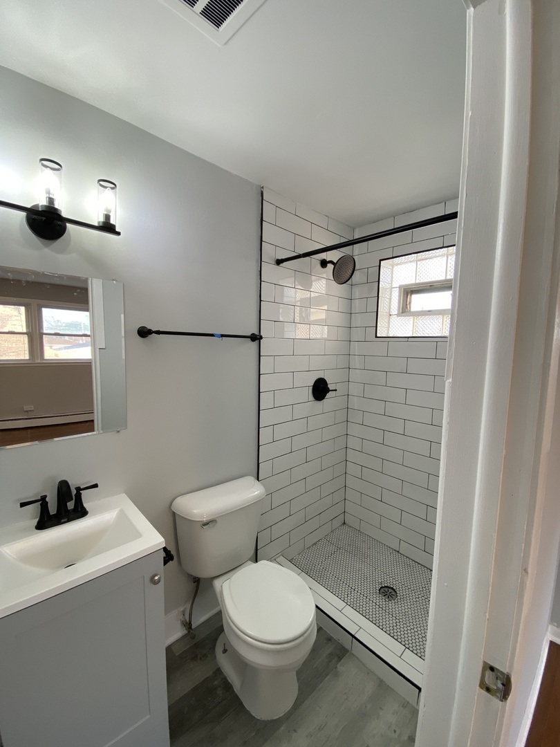 5822 West 79th Street, Unit 1 Burbank, IL 60459 - Photo 4 of 5 a bathroom with a toilet a sink a mirror and shower