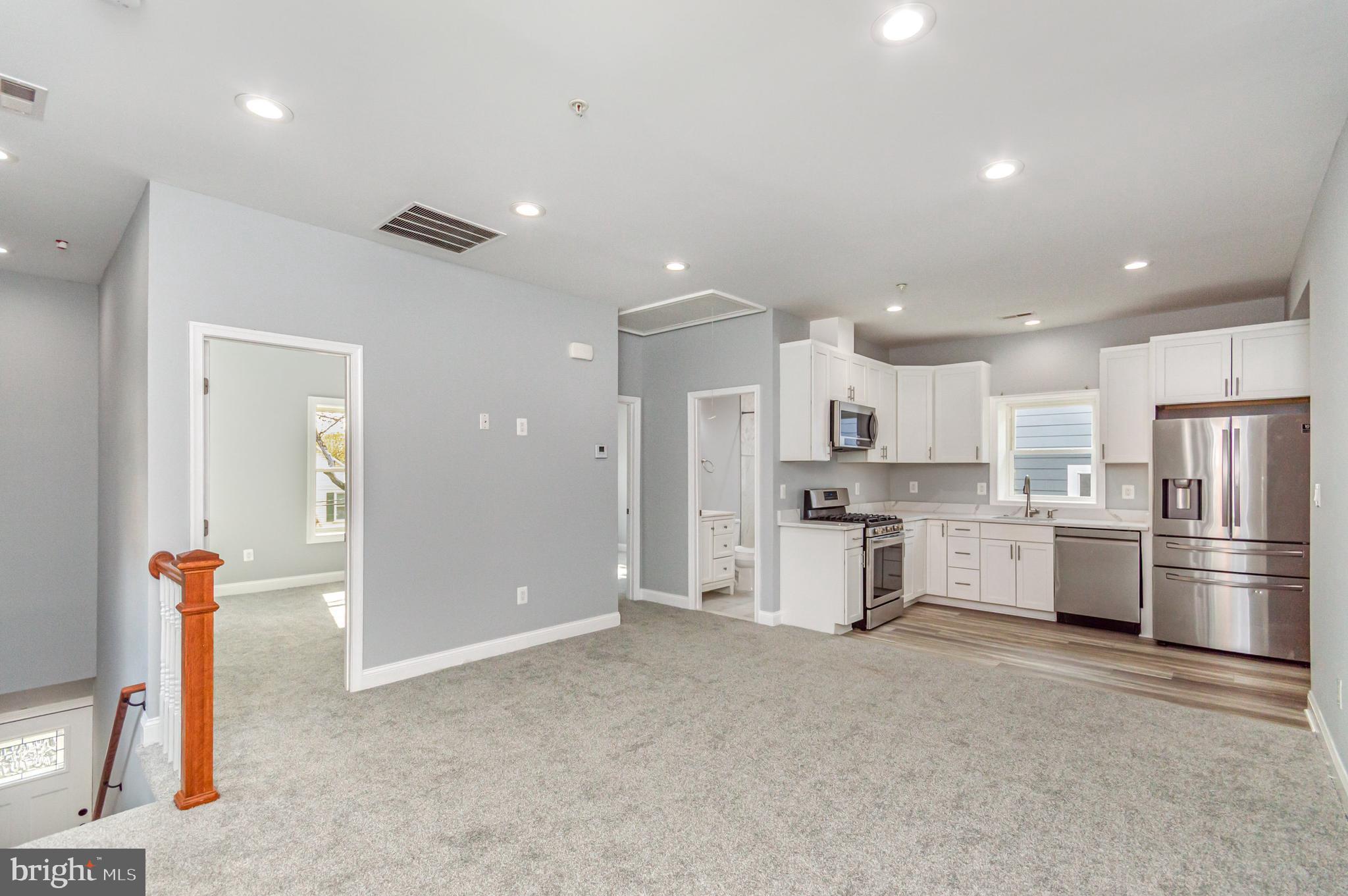 3110 Perry Street, Unit B Mount Rainier, MD 20712 - Photo 23 of 24 a large kitchen with white cabinets and stainless steel appliances