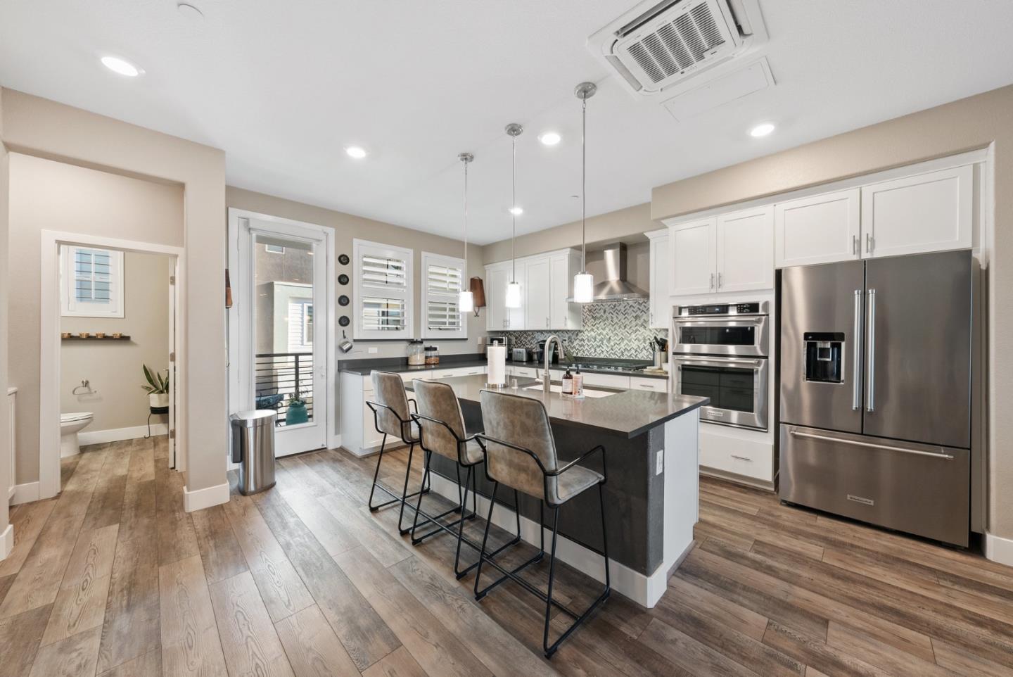 6725 Magnetic Loop San Jose, CA 95119 - Photo 13 of 68 a kitchen with kitchen island wooden floors white appliances and cabinets