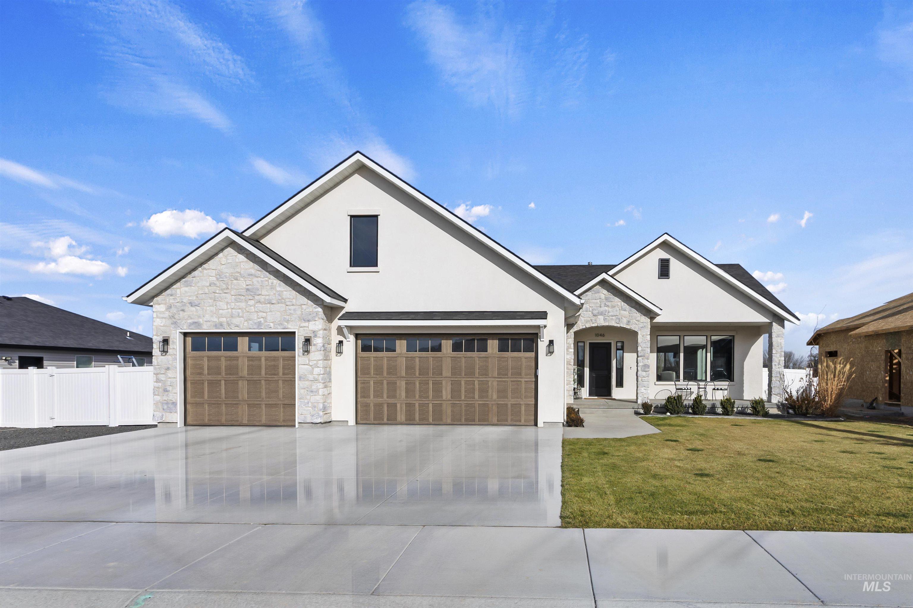 View of front of house with stone siding, driveway, and stucco siding