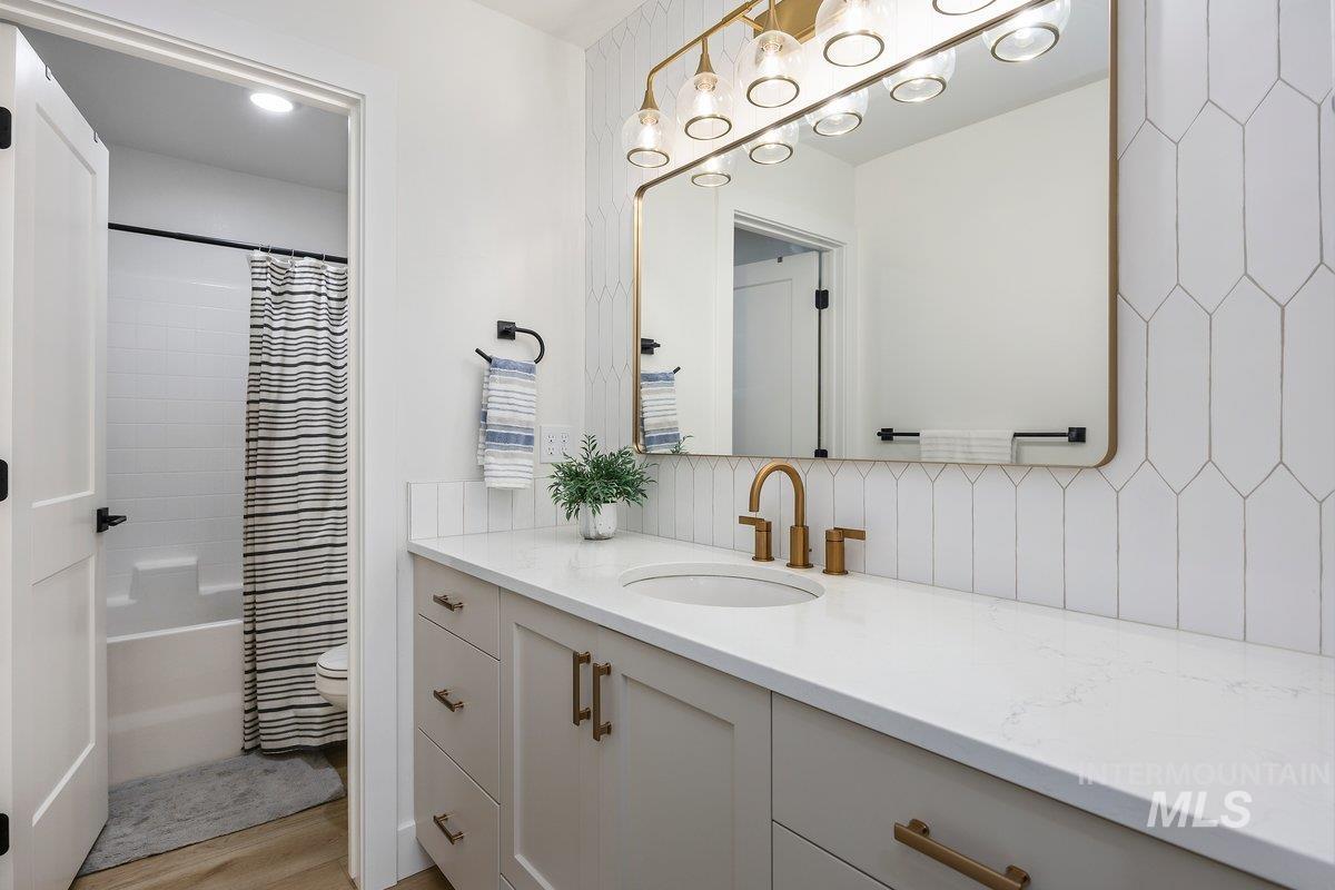 1046 Northridge Way Kimberly, ID 83341 - Photo 16 of 24 Bathroom featuring vanity, shower / tub combo with curtain, light wood finished floors, and decorative backsplash