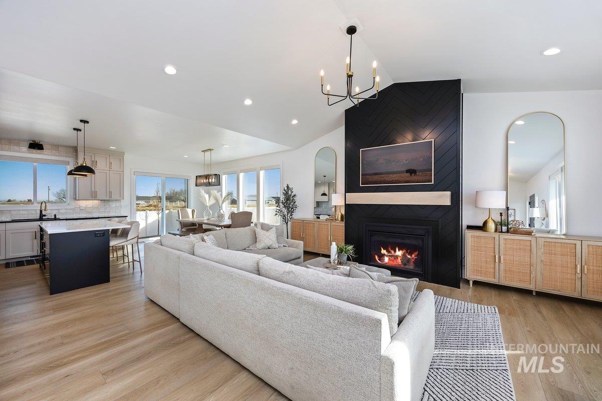 1046 Northridge Way Kimberly, ID 83341 - Photo 2 of 24 Living room featuring vaulted ceiling, arched walkways, a large fireplace, light wood finished floors, and a chandelier