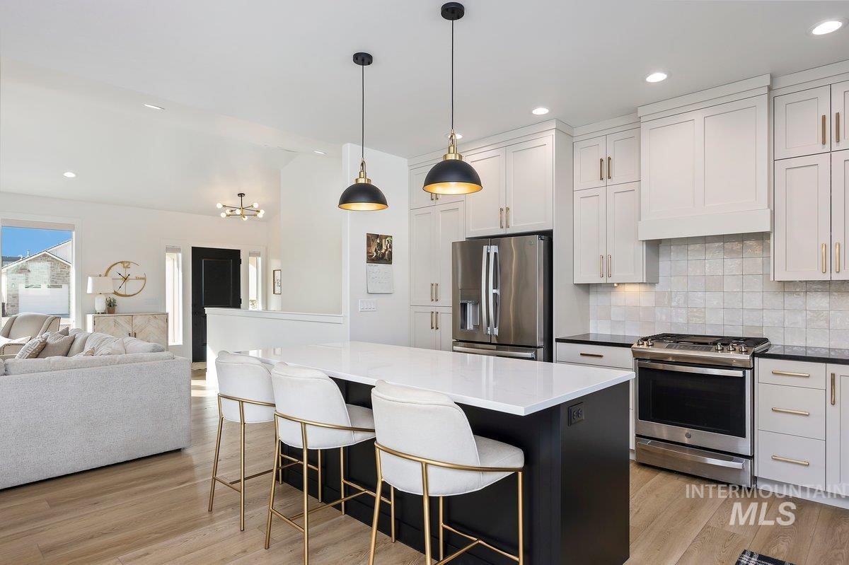 1046 Northridge Way Kimberly, ID 83341 - Photo 24 of 24 Two tone kitchen with stainless steel appliances, a breakfast bar, open floor plan, light wood finished floors, and decorative backsplash