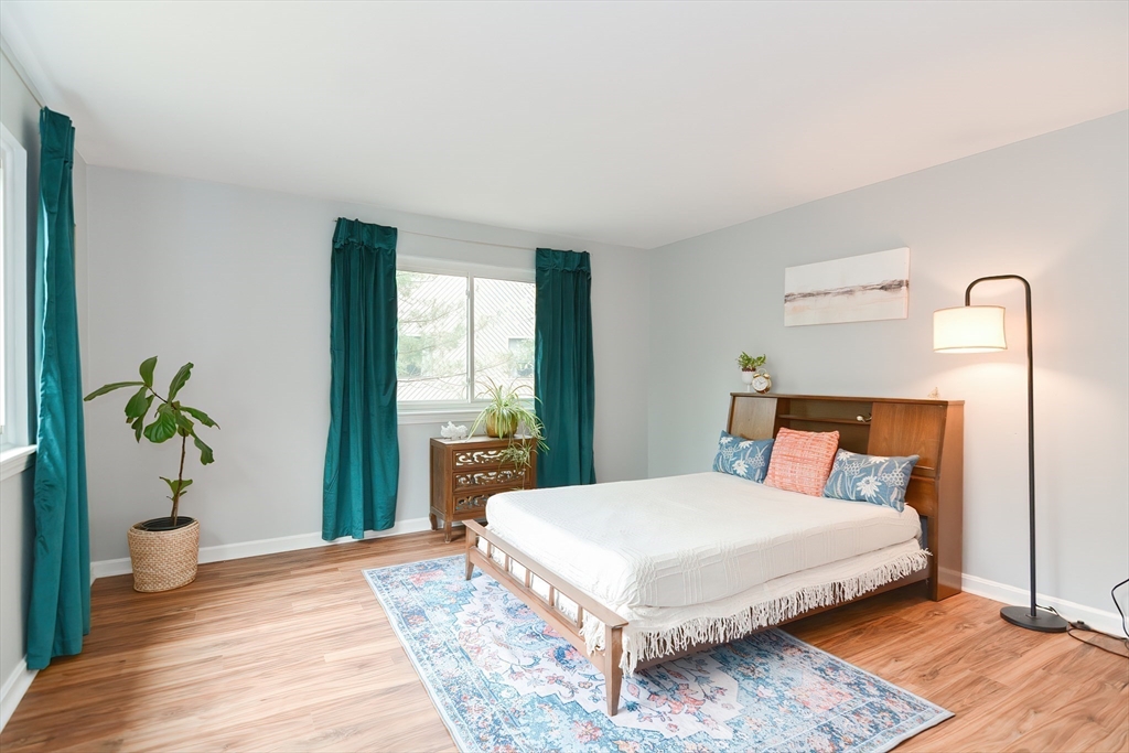65 Mountain Gate Road, Unit 65 Ashland, MA 01721 - Photo 23 of 32 a bedroom with a large bed and a potted plant