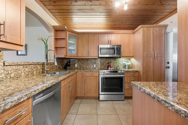 a kitchen with kitchen island granite countertop a sink stainless steel appliances and cabinets
