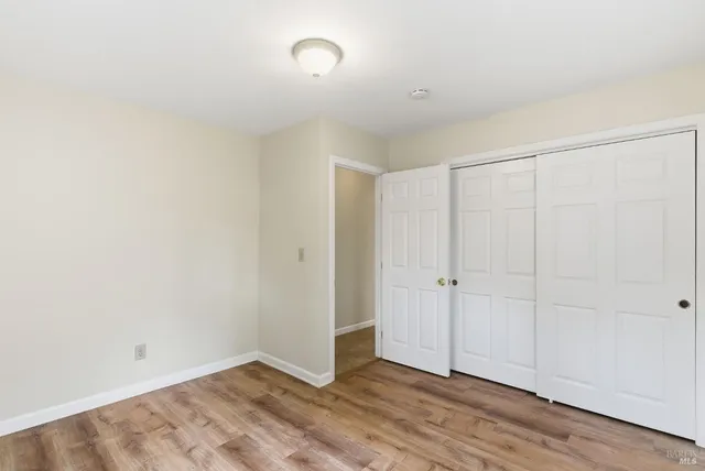 an empty room with wooden floor and closet