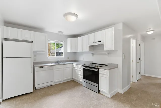 a kitchen with stainless steel appliances granite countertop white cabinets a refrigerator a sink a stove a microwave and white cabinets