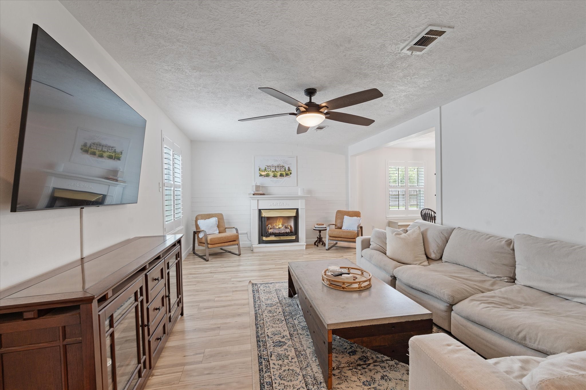 110 Dozent Lane Baytown, TX 77521 - Photo 6 of 36 Spacious living room featuring a cozy fireplace, elegant ceiling fan, and abundant natural light, perfect for relaxation and entertaining.