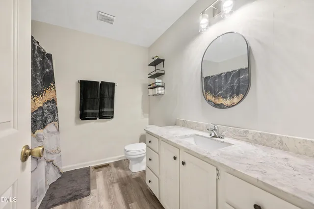 a bathroom with a granite countertop toilet a sink and a mirror
