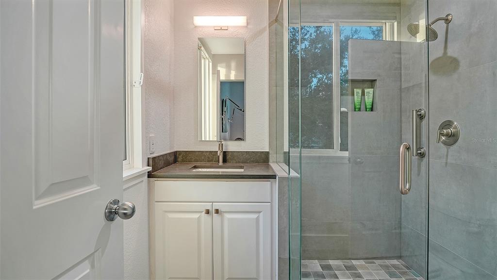 166 Golden Gate Point, Unit 22 Sarasota, FL 34236 - Photo 31 of 51 a bathroom with a granite countertop sink a mirror and shower