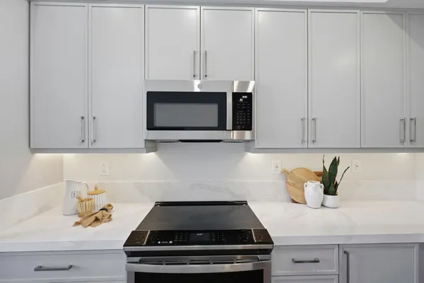 a kitchen with white cabinets and appliances
