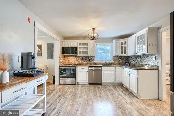 a kitchen with stainless steel appliances granite countertop a stove top oven a sink dishwasher and a refrigerator with wooden floor