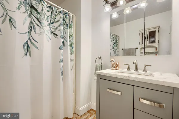 a bathroom with a granite countertop sink a mirror a vanity and shower curtain