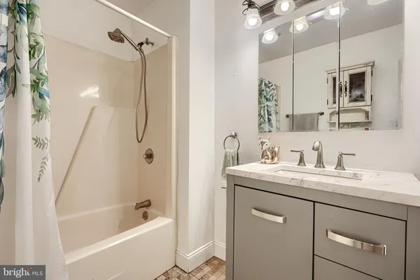 a bathroom with a tub a sink a mirror a vanity and shower
