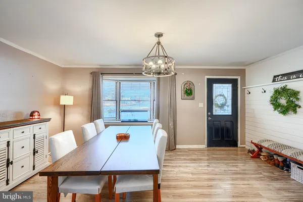 a dining room with wooden floor a chandelier a wooden table and chairs
