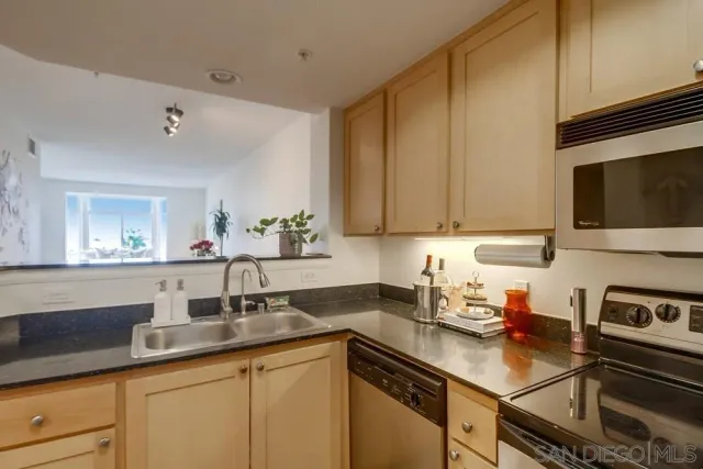 a kitchen with stainless steel appliances granite countertop a refrigerator a stove a sink and a microwave