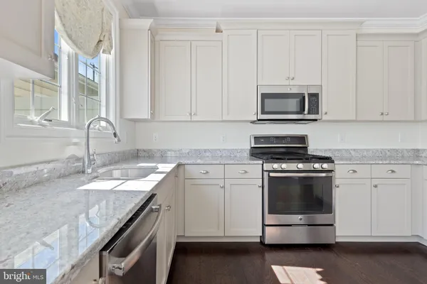 a kitchen with granite countertop white cabinets and stainless steel appliances