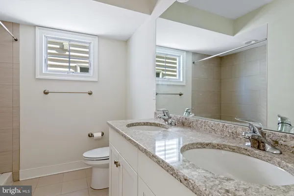 a bathroom with a granite countertop sink a mirror and a toilet