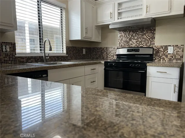 a kitchen with stainless steel appliances granite countertop a sink stove refrigerator and cabinets