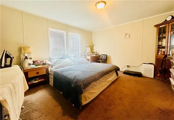 a bedroom with bed and a flat tv screen on dresser