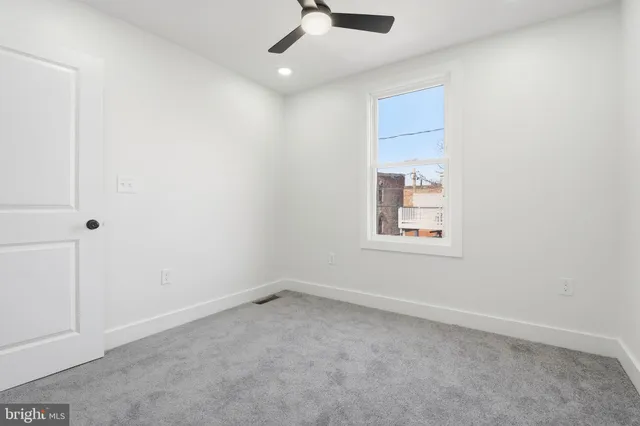 an empty room with a ceiling fan and window