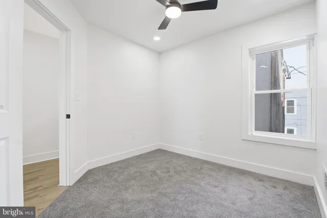 an empty room with windows and ceiling fan