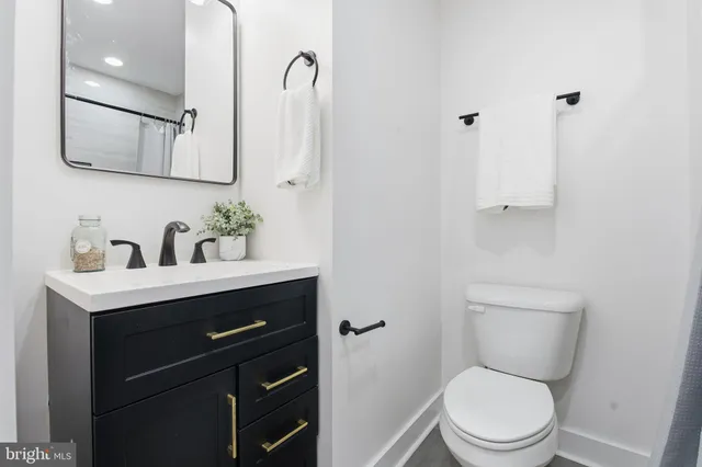 a bathroom with a toilet sink vanity granite and mirror