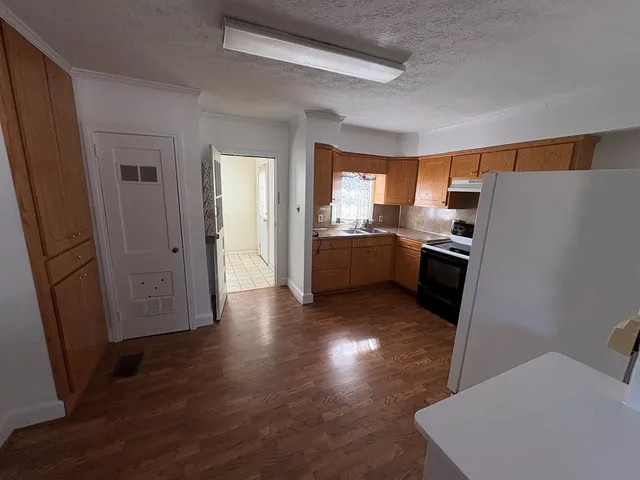 a kitchen with granite countertop a refrigerator stove and wooden floor