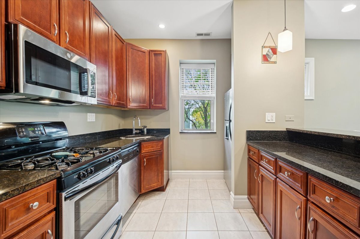 1265 West Granville Avenue, Unit 3 Chicago, IL 60660 - Photo 6 of 15 a kitchen with stainless steel appliances granite countertop a stove a sink and a microwave