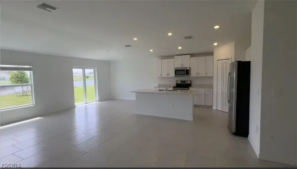 a view of a kitchen with kitchen island wooden floors and stainless steel appliances