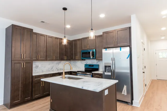 a kitchen with kitchen island a refrigerator a sink and wooden cabinets