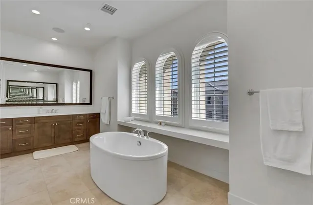 a spacious bathroom with a tub double sink and mirror
