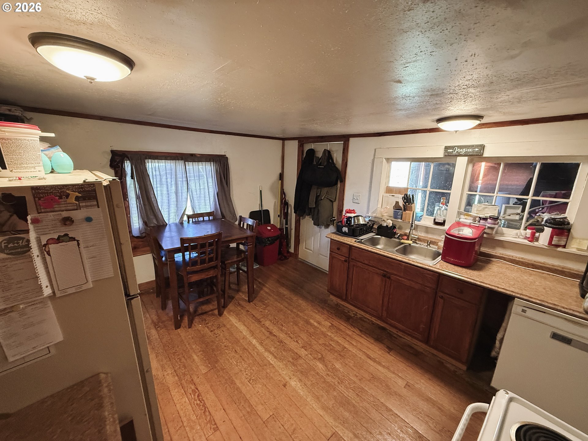 827 East 11th Street Coquille, OR 97423 - Photo 26 of 45 a kitchen with stainless steel appliances kitchen island granite countertop a refrigerator a sink dishwasher a dining table and chairs with wooden floor