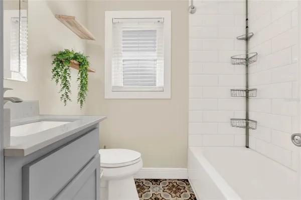 a bathroom with a sink a toilet a window and shower