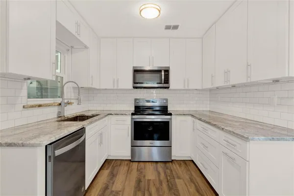 a kitchen with granite countertop a stove a sink and a microwave