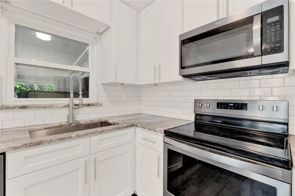 a kitchen with stainless steel appliances granite countertop a sink stove and microwave