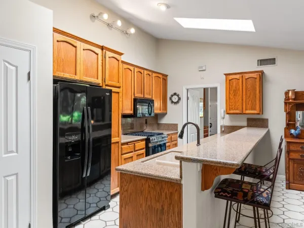a kitchen with granite countertop a refrigerator a stove a sink a dining table and chairs with wooden floor