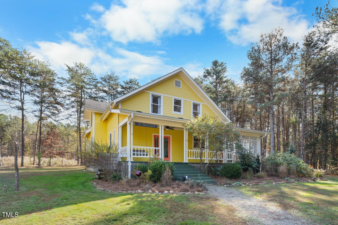 a view of a yard in front of a house with plants and large trees