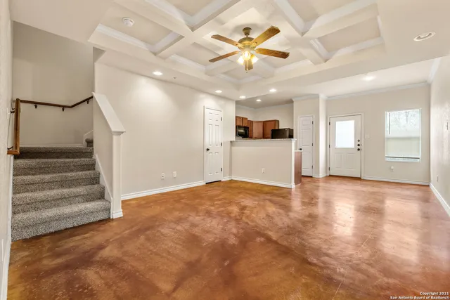 a view of an empty room with wooden floor and a ceiling fan