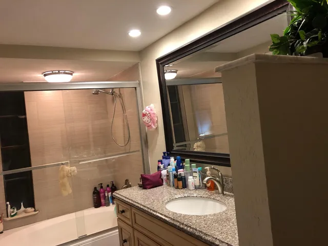 a bathroom with a granite countertop sink a mirror and shower