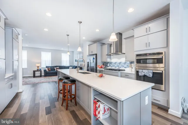 a kitchen with kitchen island a stove a sink a refrigerator and chairs