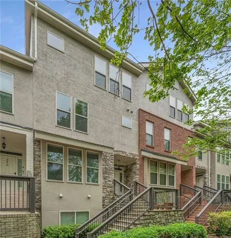 front view of a brick house with a yard and large trees