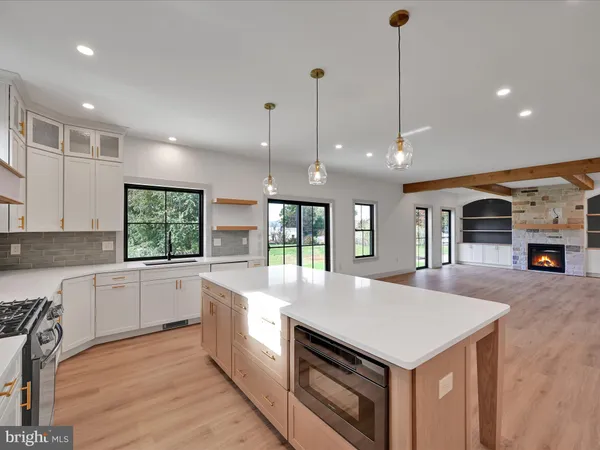 a large kitchen with kitchen island a stove a sink a center island and wooden floor